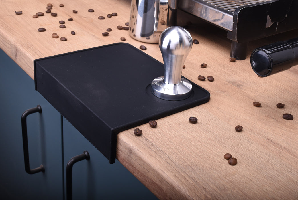 Tamper mat with tamper next to a espresso machine and a milkpitcher. espresso tamping mat for excellent barista tools