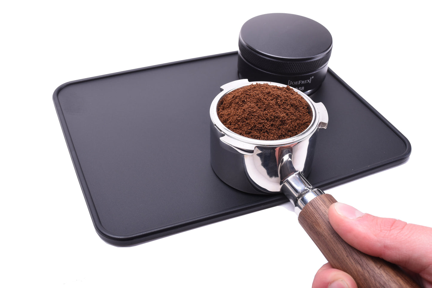 portafilter on tamper mat. portafilter filled with coffee. on the tamper rest of the tamping mat ist the espresso distributor. tamping mat shows that you  can perfectly use it as tamping station