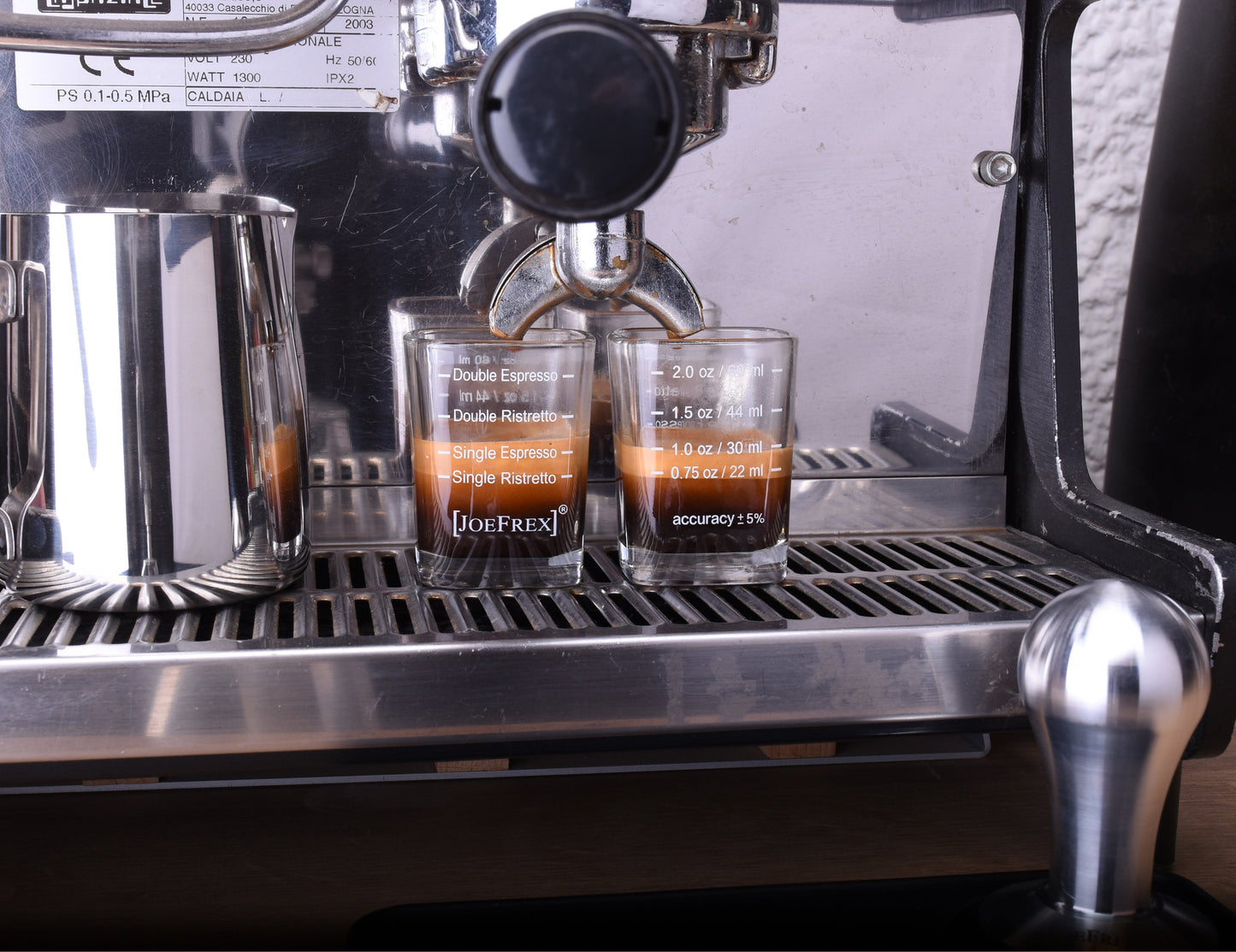 espresso shot glasses under a espresso machine. filled with espresso. shown as a perfect barista tool for coffee interested people, which search for tools for barista